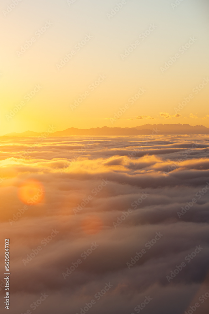 Above the clouds at sunset with sun flares