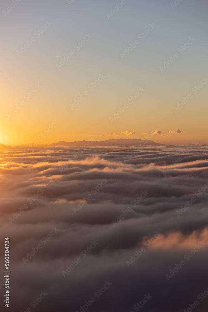 Above the clouds at sundown with mountains in the background