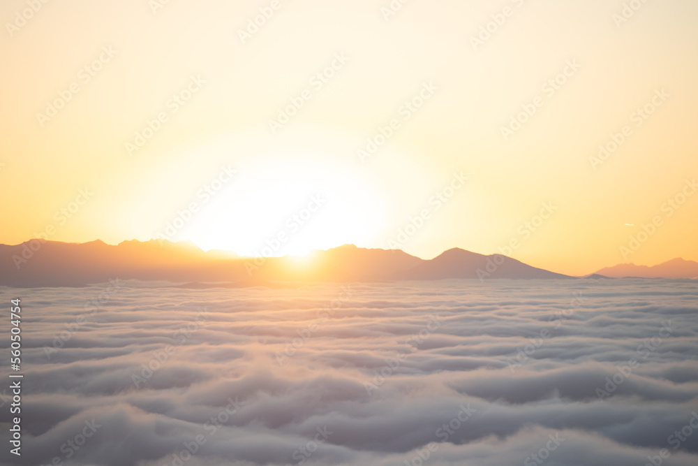 Sea of clouds at sunset with mountains in the background