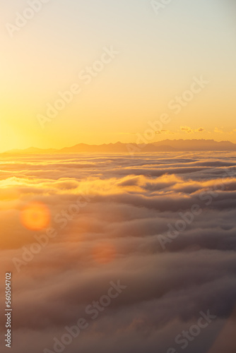Above the clouds at sunset with sun flares