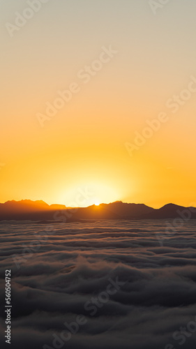 Ocean of clouds at sunset with mountains in the background