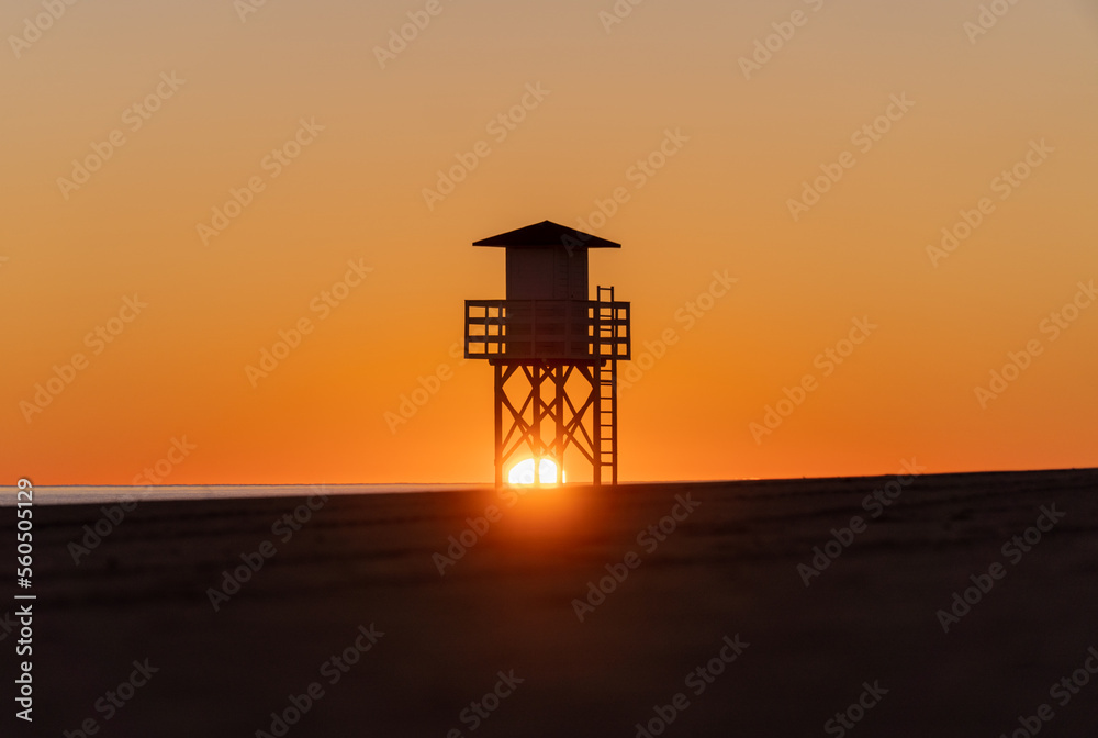 The sun behind the lifeguard post on the empty beach at sunrise The sun behind the lifeguard post on the empty beach at sunrise