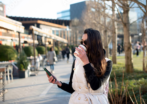 Happy woman drinking coffee reading online morning news on smartphone