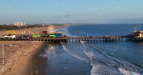 Aerial Panning Shot Of People At Famous Santa Monica Pier In City, Drone Flying Over Sea At Beach photo