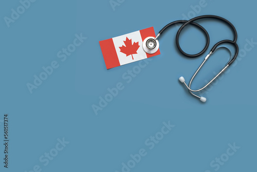 Overhead flat lay of a doctor's stethoscope with the Canadian flag against a blue background photo