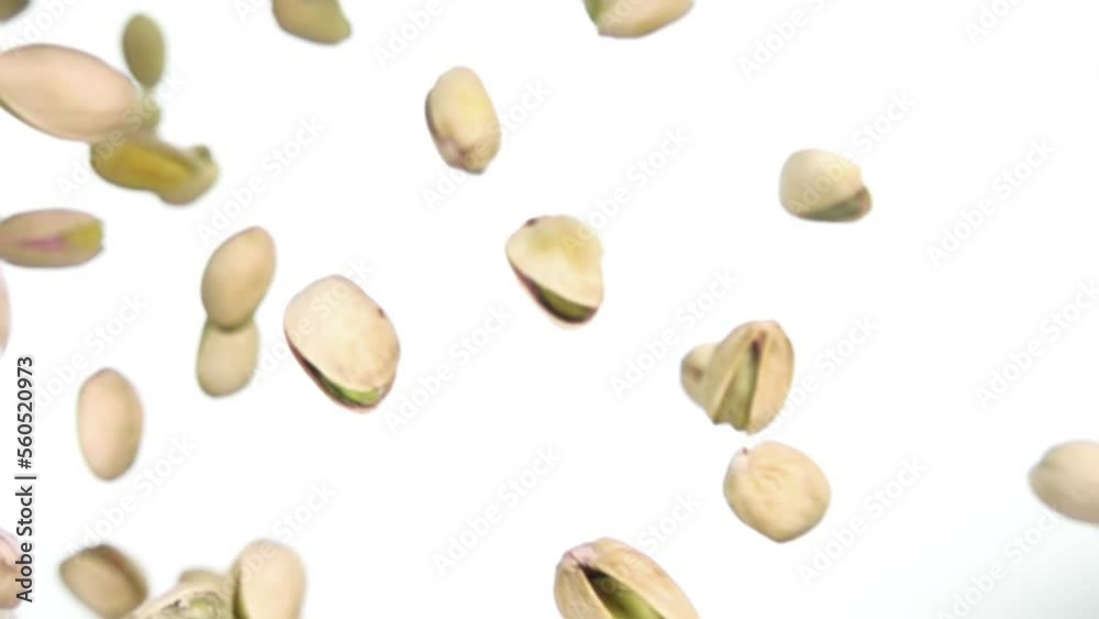 Close-up top view of the delicious salted Pistachios falling on a white background Close-up top view of the delicious salted Pistachios falling on a white background