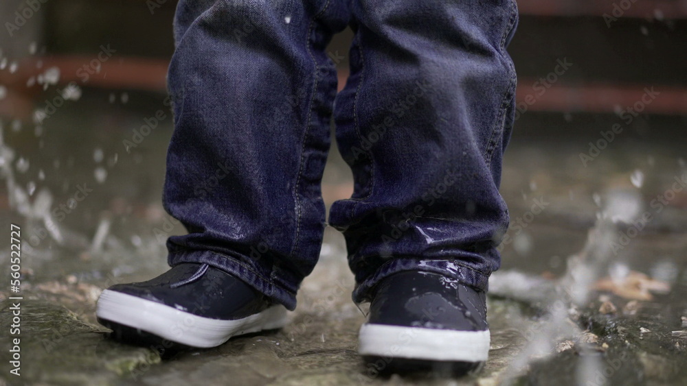 Toddler boy splashes into puddle of water. Child plays with puddles13