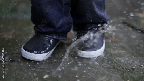 Toddler boy splashes into puddle of water. Child plays with puddles11