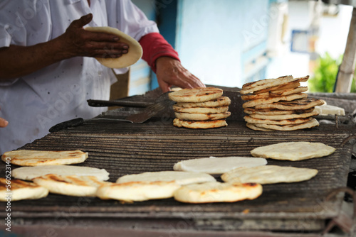Woman's hands grilling Colombian arepas at a traditional stand in the streets of Colombia.
