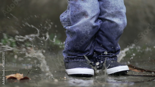 Toddler boy splashes into puddle of water. Child plays with puddles6