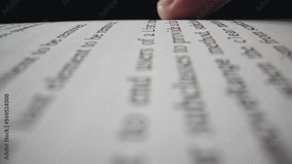 Cropped view of the page with a text in English and forefinger pointing text while reading book Cropped view of the page with a text in English and forefinger pointing text while reading book