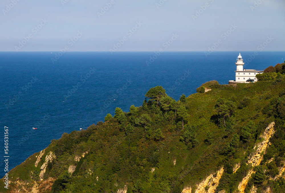 Lighthouse on Mountainside in spain, with blue sea background