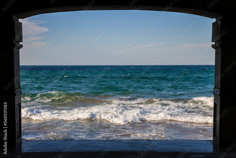 Blue Sea waves on a clear day seeing through a structure frame silhouette