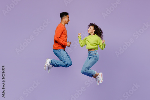 Full body sideways overjoyed young couple two friends family man woman of African American ethnicity wears casual clothes together do winner gesture isolated on pastel plain light purple background.