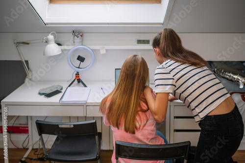 Two young girls studying in their room.