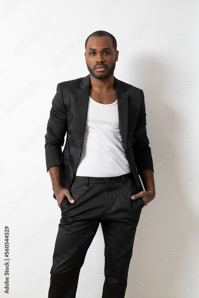 Portrait of dark-skinned finance banker clerk wearing trendy casual suit holding hands in pockets posing over isolated white color background. Portrait of dark-skinned finance banker clerk wearing trendy casual suit holding hands in pockets posing over isolated white color background.