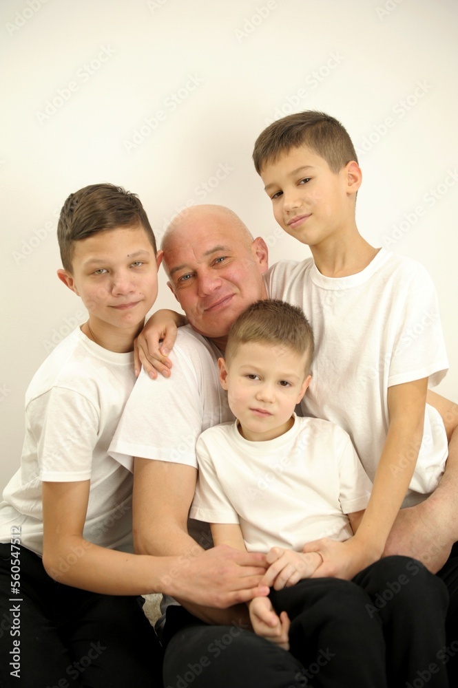 photo of father three sons children stuck around dad from all sides it is difficult for father to keep them all in white t-shirts on white background adoption concept joy help family large family photo of father three sons children stuck around dad from all sides it is difficult for father to keep them all in white t-shirts on white background adoption concept joy help family large family