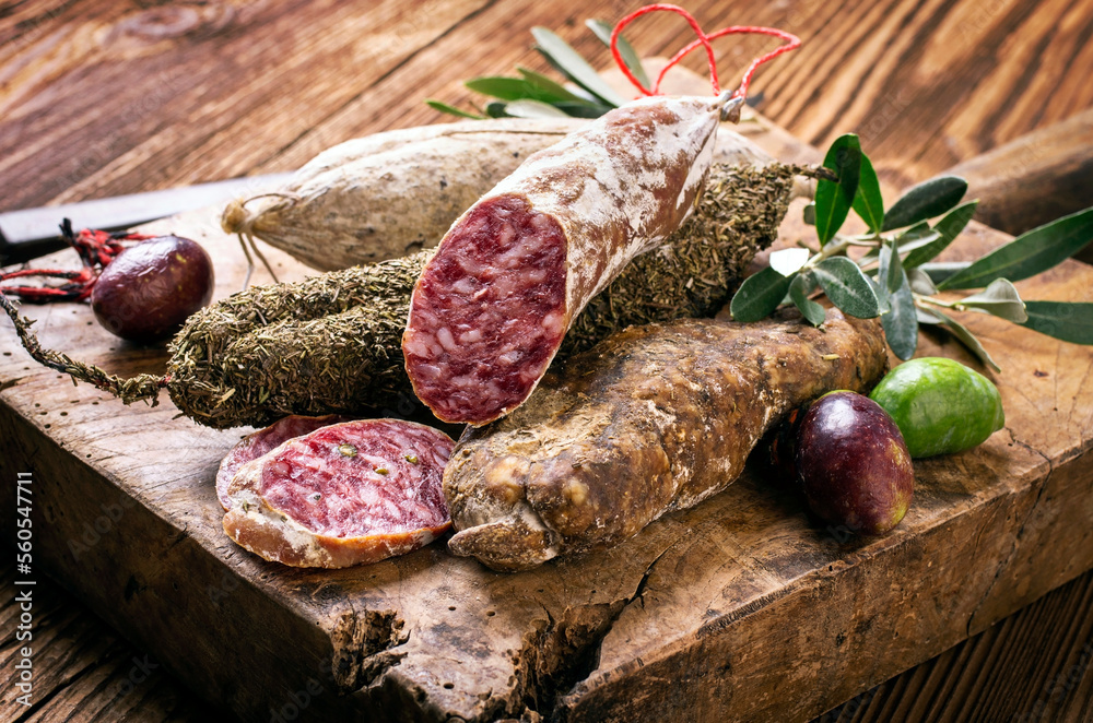 Traditional Italian salami with black ripe olives served as close-up on an old wooden cutting board Traditional Italian salami with black ripe olives served as close-up on an old wooden cutting board