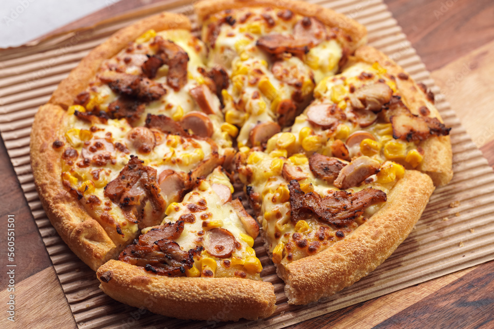 Freshly baked american pan pizza with a lot of cheese, chicken sausage, thin and crispy kebab meat and corn on a wooden board, take-away dish Freshly baked american pan pizza with a lot of cheese, chicken sausage, thin and crispy kebab meat and corn on a wooden board, take-away dish