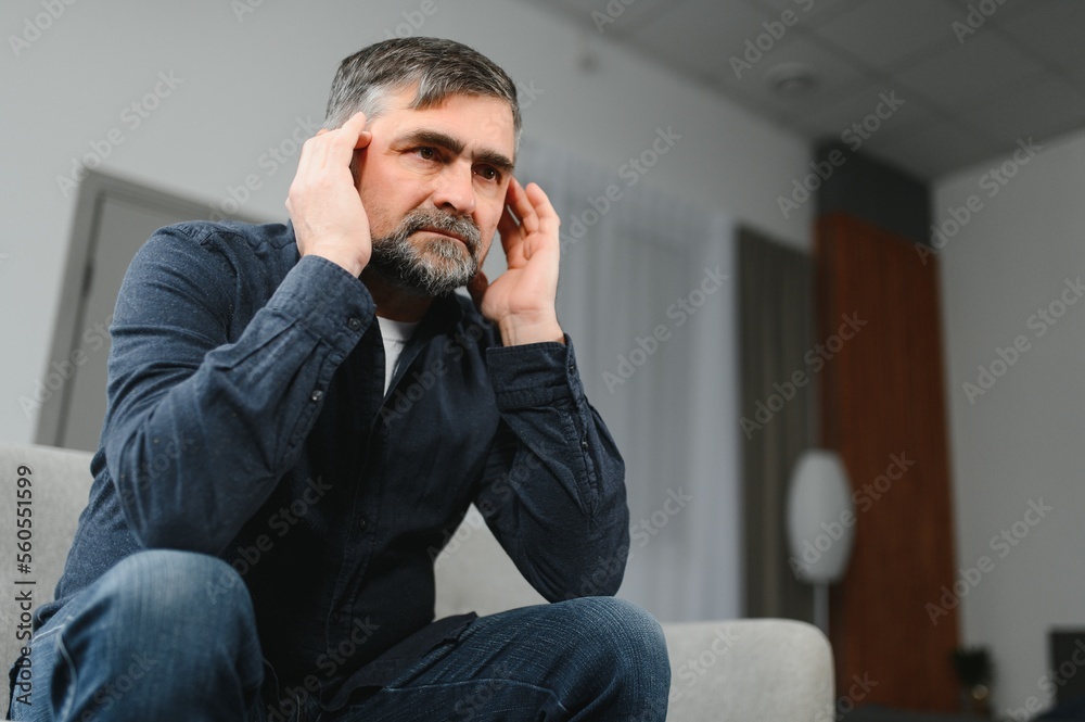 Closeup of middle-aged bearded man suffering from headache at home, touching his temples, panorama with copy space. Migraine, headache, stress, tension problem, hangover concept Closeup of middle-aged bearded man suffering from headache at home, touching his temples, panorama with copy space. Migraine, headache, stress, tension problem, hangover concept
