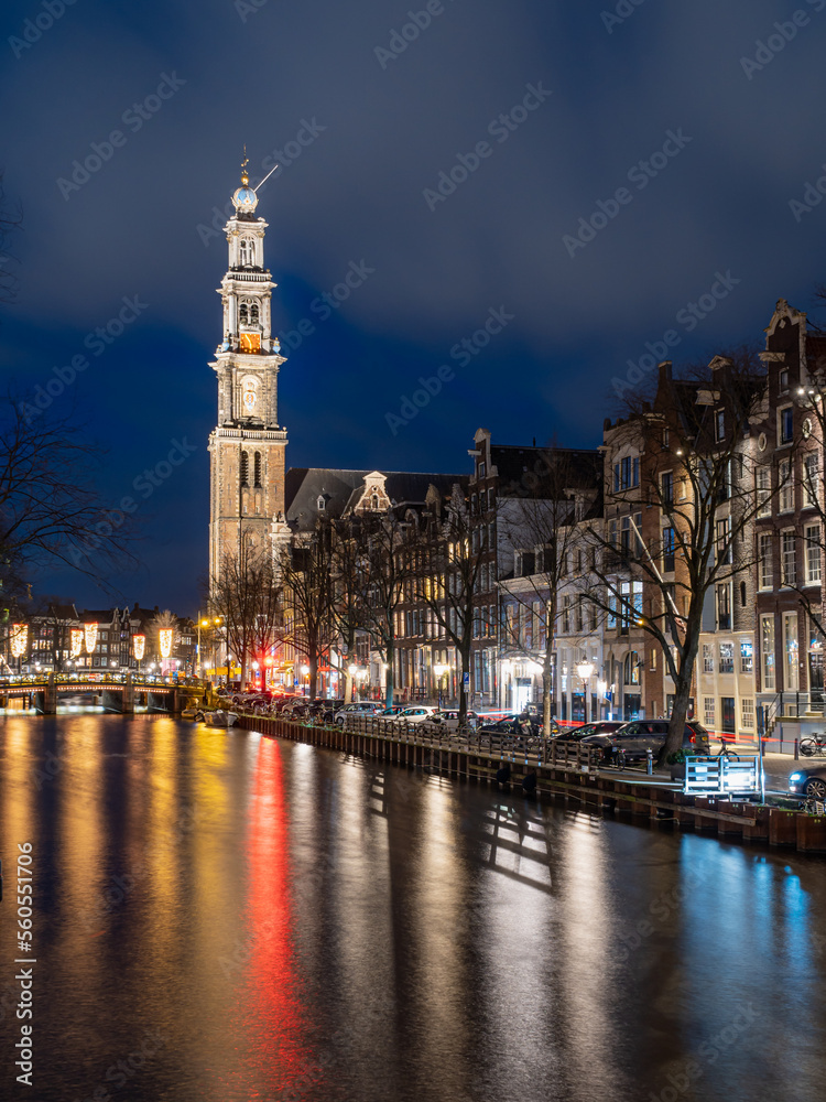 Night view of the western church from canal in Amsterdam.