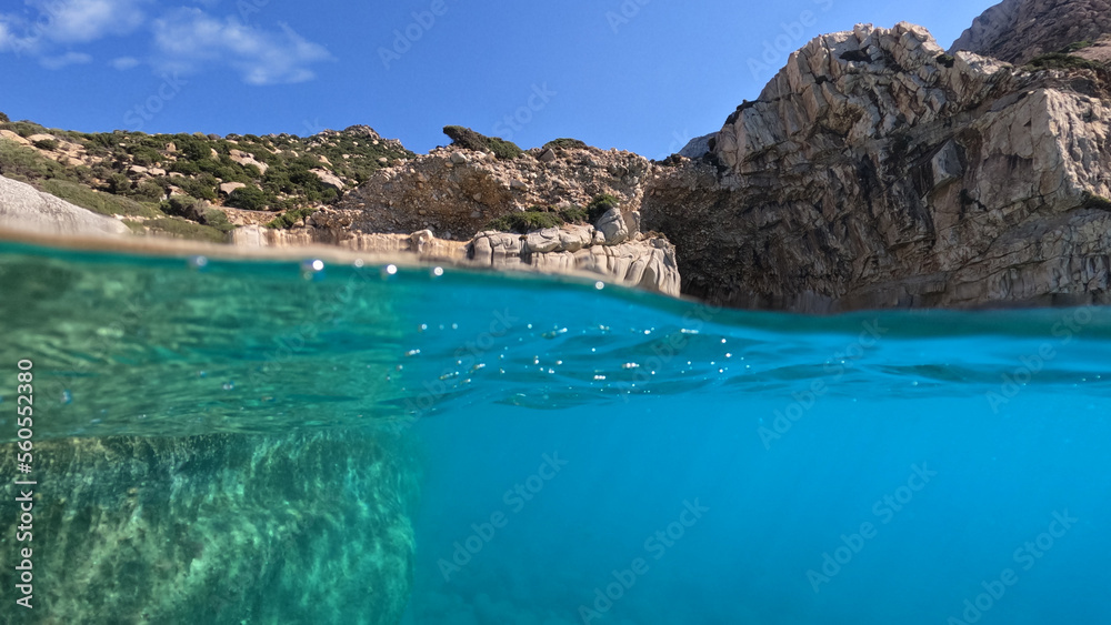 Fototapeta premium Underwater split photo of paradise exotic volcanic white rock island pebble beach with crystal clear turquoise sea in Caribbean destination island forming a blue lagoon