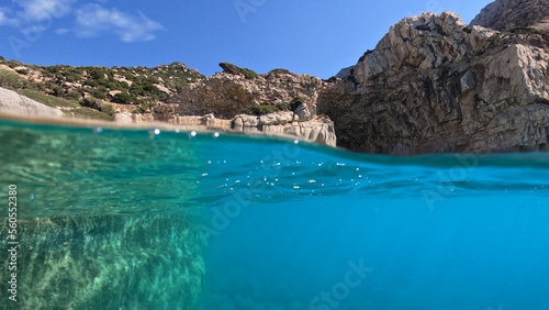 Underwater split photo of paradise exotic volcanic white rock island pebble beach with crystal clear turquoise sea in Caribbean destination island forming a blue lagoon