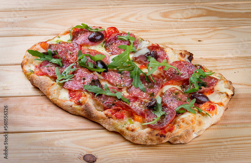 Pizza Diavolo with chorizo, rucola, jalapeno, chili, kalamata, pesto. Roman pizza rectangular on wood background
