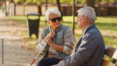 Blind elderly woman with her husband sitting on a bench in the park. High quality photo © CameraCraft