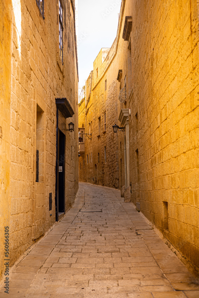 Warm street of the Maltese city of Valletta. Yellow stone for walls and road.