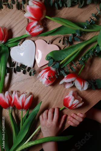 Bouquet of tulips on the table with hearts. Valentines, mothers, women's day, wedding or birthday flat lay concept. Top view.