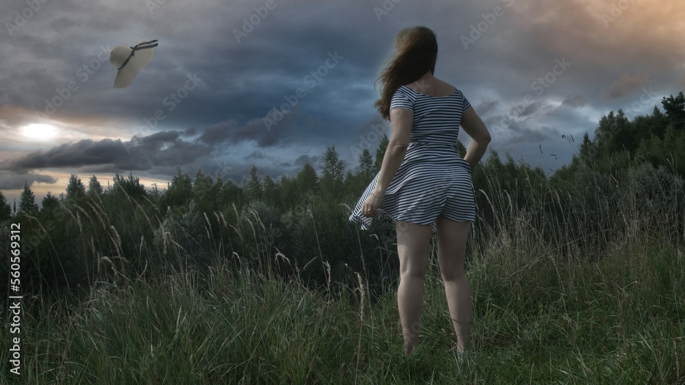 Wind blows off the hat. The wind rips the hat off the head of a woman in nature in cloudy weather. Wind blows off the hat. The wind rips the hat off the head of a woman in nature in cloudy weather.