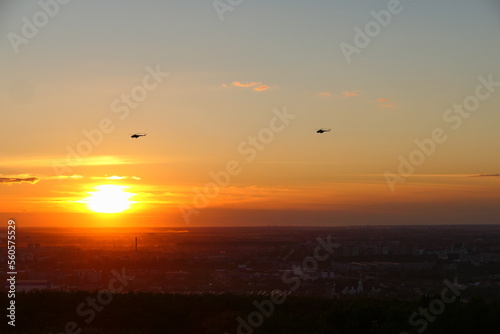 Two helicopters in the sky against the backdrop of the setting sun  Bright sunset