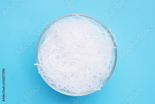 Vermicelli in glass bowl on blue background.