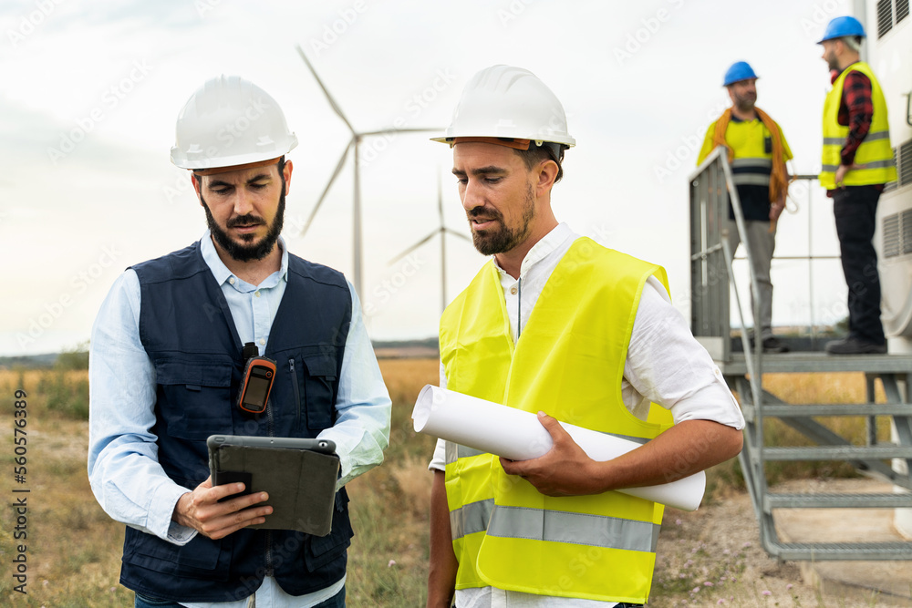 Team of Electrical Technicians and Engineers working in Wind Turbine Electricity Power Station, using tablet to do technical inspection Team of Electrical Technicians and Engineers working in Wind Turbine Electricity Power Station, using tablet to do technical inspection