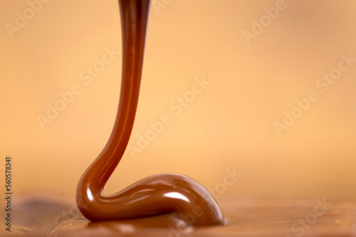 Pouring caramel milk caramel spread with a spoon on wooden background, traditional mexican sweet known as Cajeta or dulce de leche