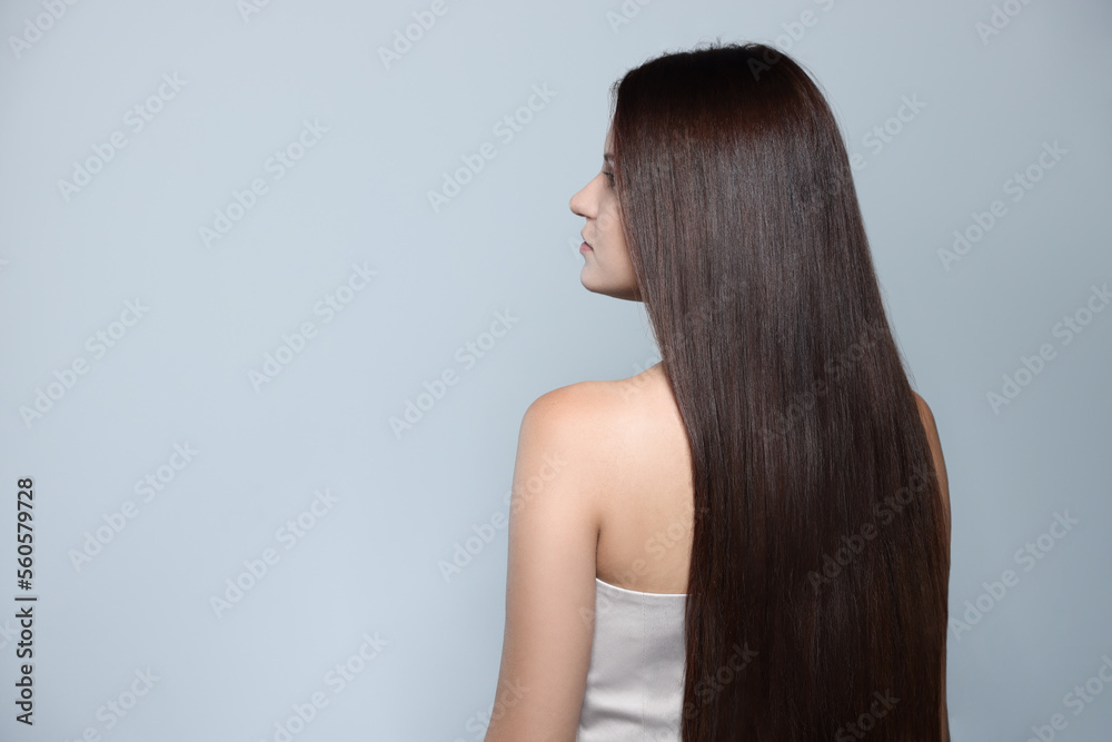 Naklejka premium Beautiful young woman with healthy strong hair on light gray background, space for text
