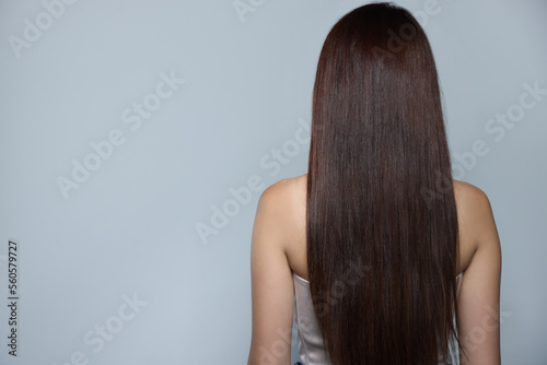 Young woman with healthy strong hair on light gray background, back view. Space for text