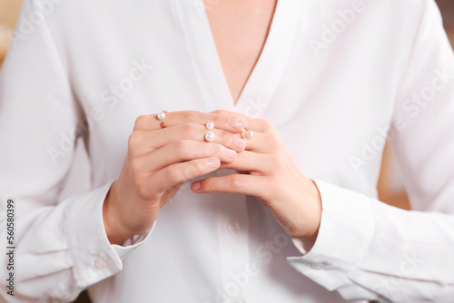 Young woman trying on elegant rings with pearls indoors  closeup