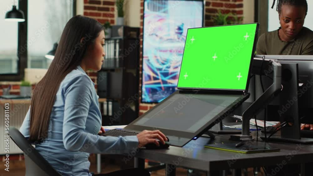 Creative agency employee looking at greenscreen and 3d developing software on touchscreen monitor. Working with isolated chroma key display and using game infographics, copyspace. Tripod shot. Creative agency employee looking at greenscreen and 3d developing software on touchscreen monitor. Working with isolated chroma key display and using game infographics, copyspace. Tripod shot.