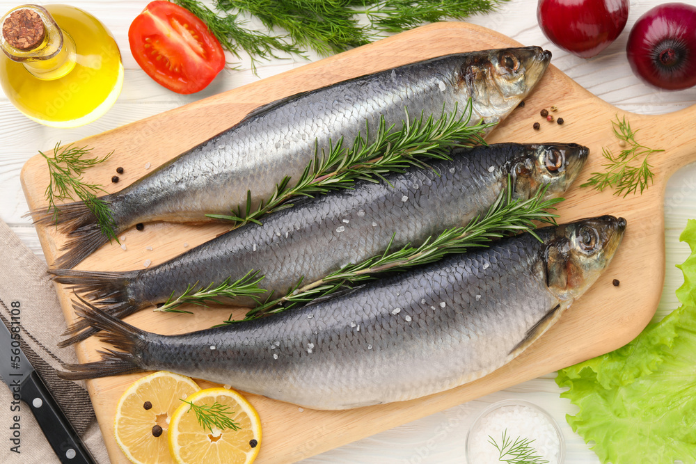 Board with delicious salted herrings and ingredients on white wooden table, flat lay Board with delicious salted herrings and ingredients on white wooden table, flat lay