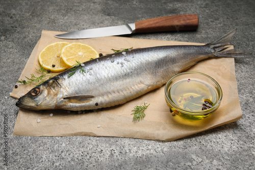 Delicious salted herring, olive oil, lemon and dill on grey table