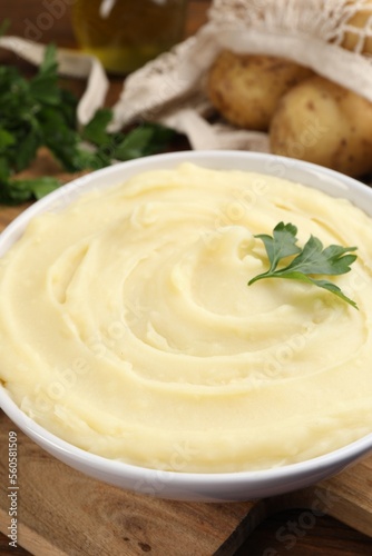 Bowl of tasty mashed potato and parsley on wooden table, closeup