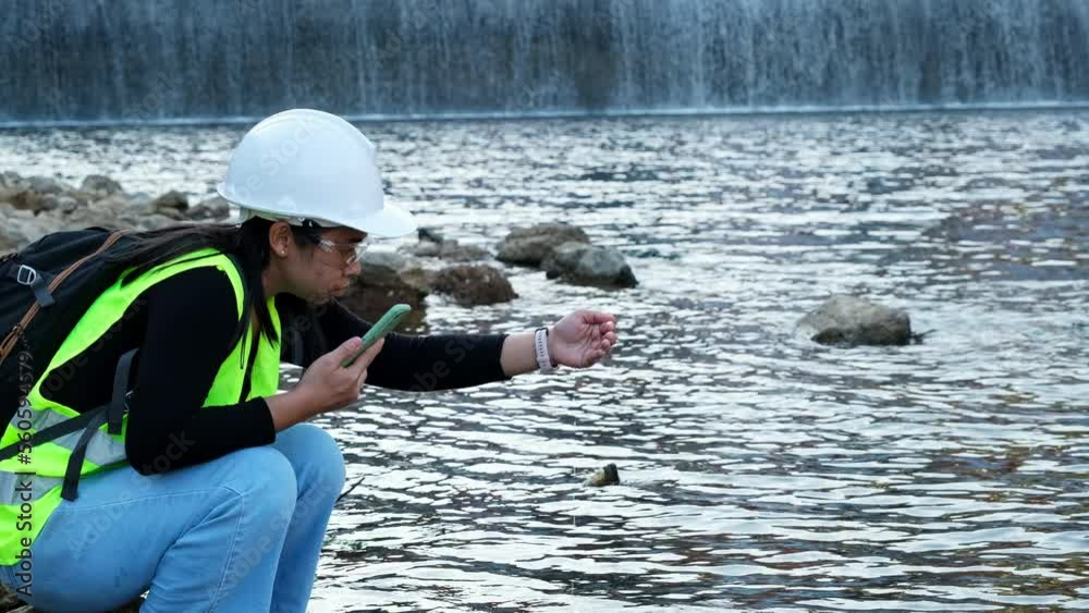 Female environmentalist using mobile phone to record water analysis data in dam. Researchers are collecting water samples from the river to test and detect pathogens. Water and ecology concept Female environmentalist using mobile phone to record water analysis data in dam. Researchers are collecting water samples from the river to test and detect pathogens. Water and ecology concept
