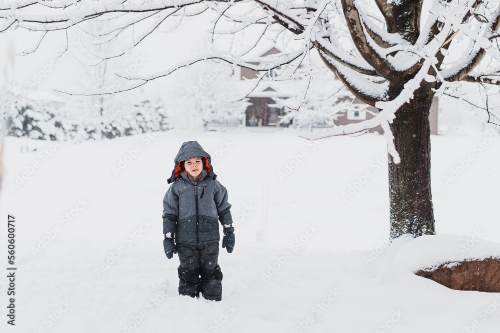 Boy standing in the snow outside in winter