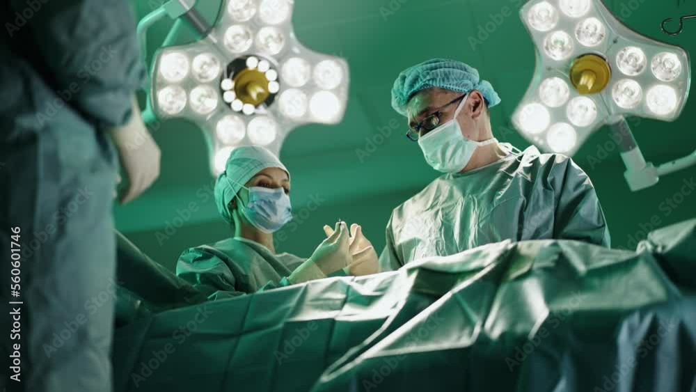 Nurse passing instruments to a surgeon while he is Performing a srugery in a hospital. 