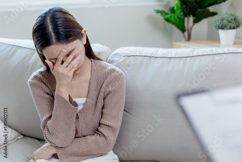 Young female sitting with her hands covering her face, feeling stressed and worried. Unhappy asian woman sitting alone. Sad women have mental symptoms illnesses and depression.