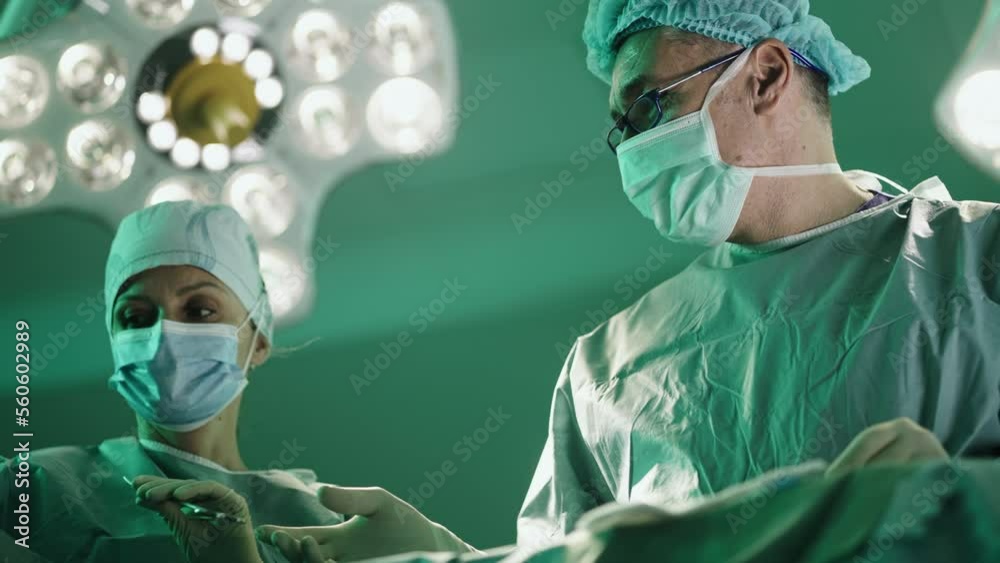 Nurse passing instruments to a surgeon while he is Performing a srugery in a hospital. 