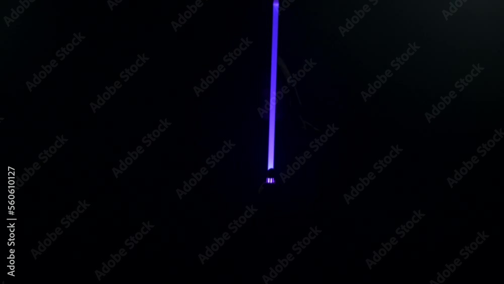 Young man in Jedi cosplay costume with lightsaber battle on black background in smoke and rain, 4k slow motion video filmed on 8k camera nikon z9