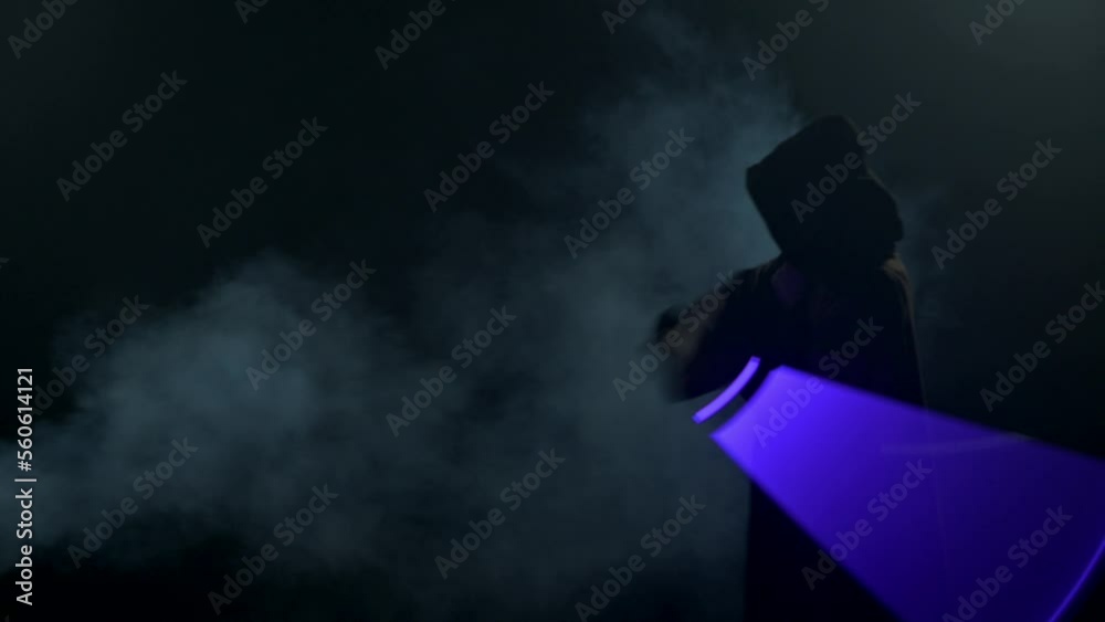 Young man in Jedi cosplay costume with lightsaber battle on black background in smoke and rain, 4k slow motion video filmed on 8k camera nikon z9